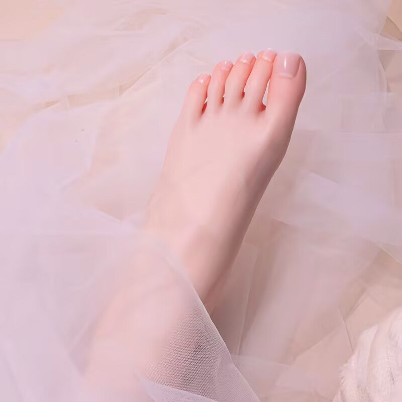 Aesthetic silicone foot model displayed on delicate white tulle fabric for luxury jewelry and bridal accessory photography