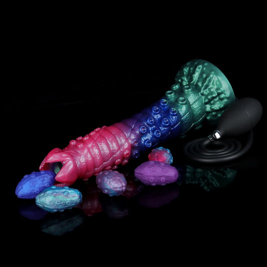 Tri-color alien egg layer dildo lying horizontally with realistic textured silicone monster eggs and a black manual squeeze bulb pump on a reflective black background.