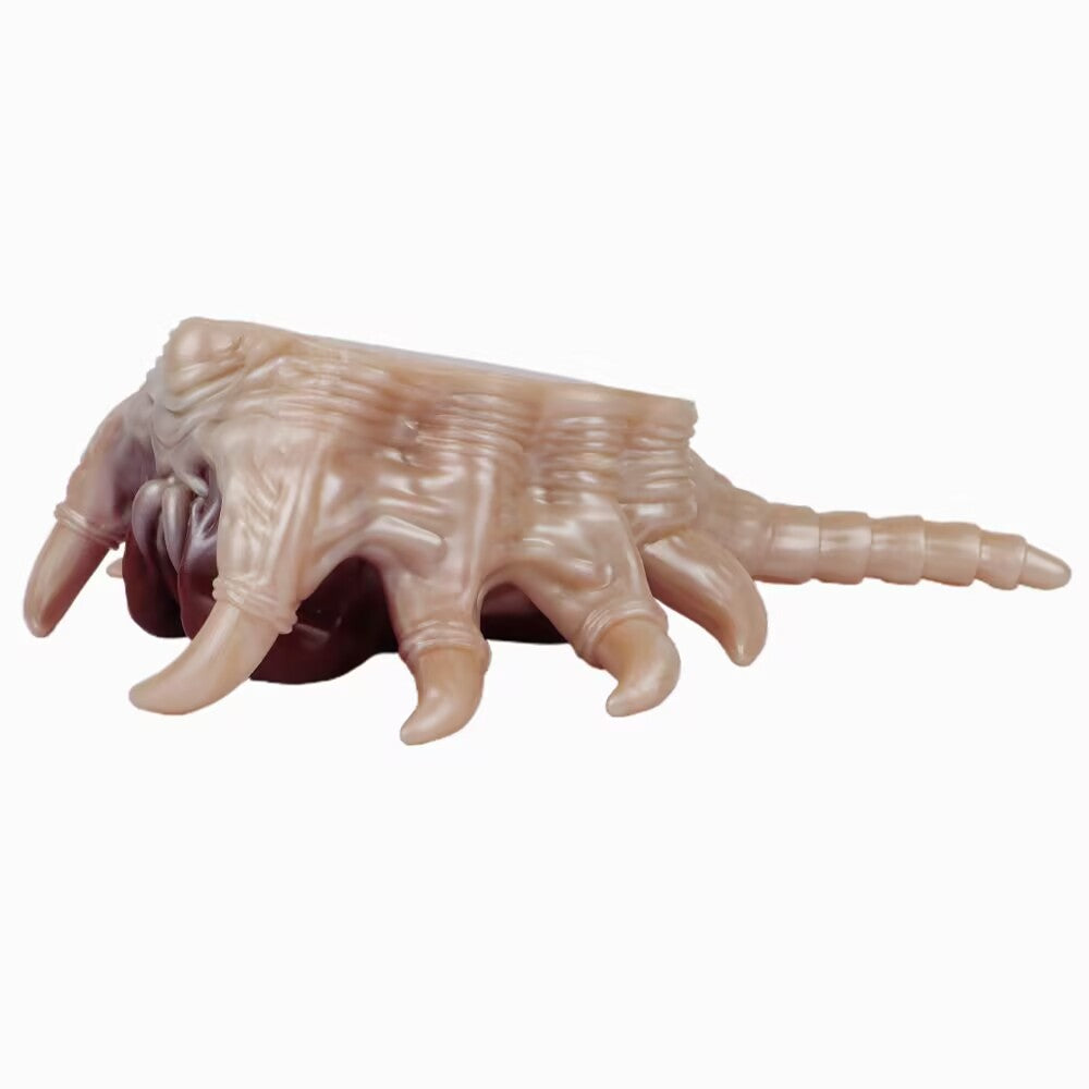 Side profile view of pale alien facehugger silicone masturbator showing legs and tail
