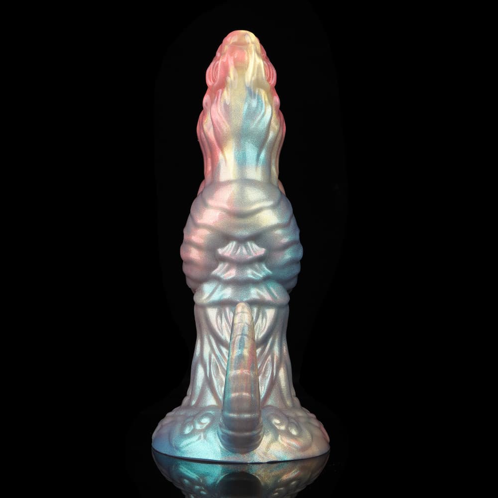 Back view of a biomorphic creature dildo highlighting the metallic blue and gold shimmering scales and a realistically detailed reptile-like tail rising from the base.