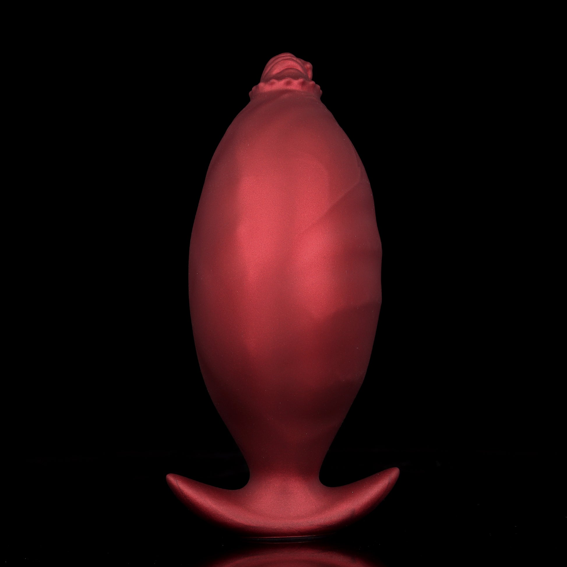 An inflated crimson red silicone expandable butt plug showcasing the contrast between the slim tip and the massive expanded body.