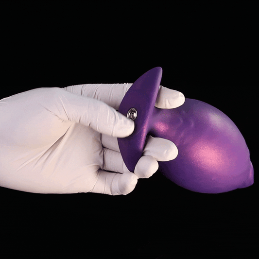 A gloved hand demonstrating the texture of the Royal Purple inflatable fantasy butt plug before inflating.