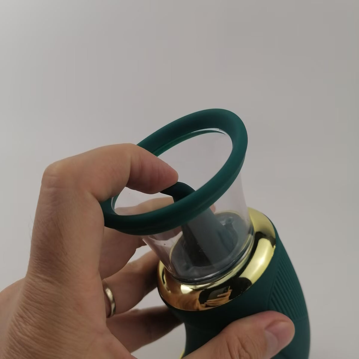Hand testing the flexible silicone tongue inside the transparent suction cup of the massager.