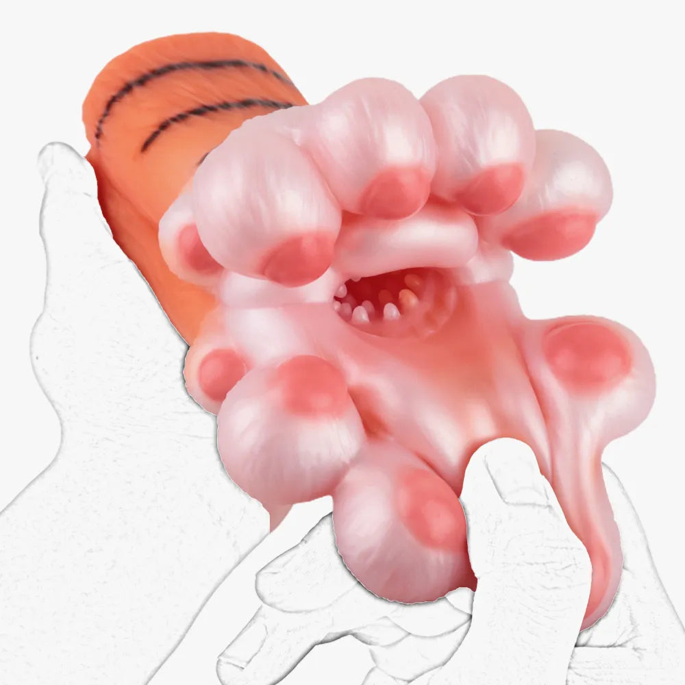 A hand squeezing and stretching the soft pink inner tunnel of the cat paw adult toy to show flexibility.