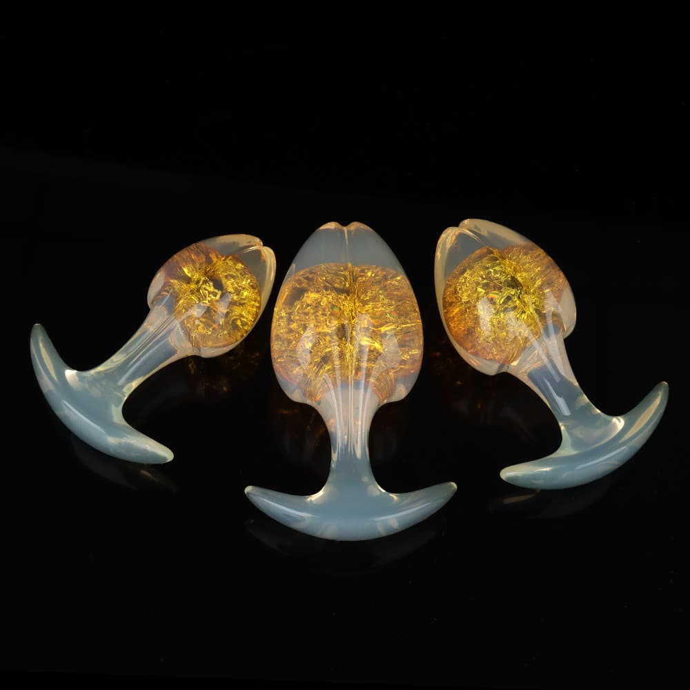 Three luminous golden-yellow sunshine crackle plugs with a luxurious opal-glow finish on a glossy black surface.