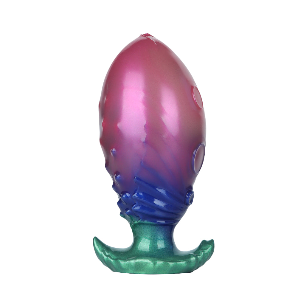 High definition shot of a pink and blue color-shift inflatable fantasy plug resting on its emerald green flared base.