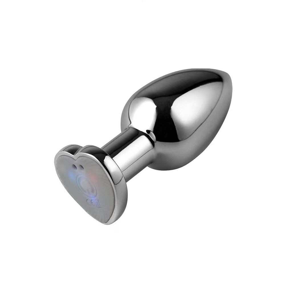 Side view of an ergonomic metallic butt plug with a heart-shaped LED light-up base for visual stimulation.