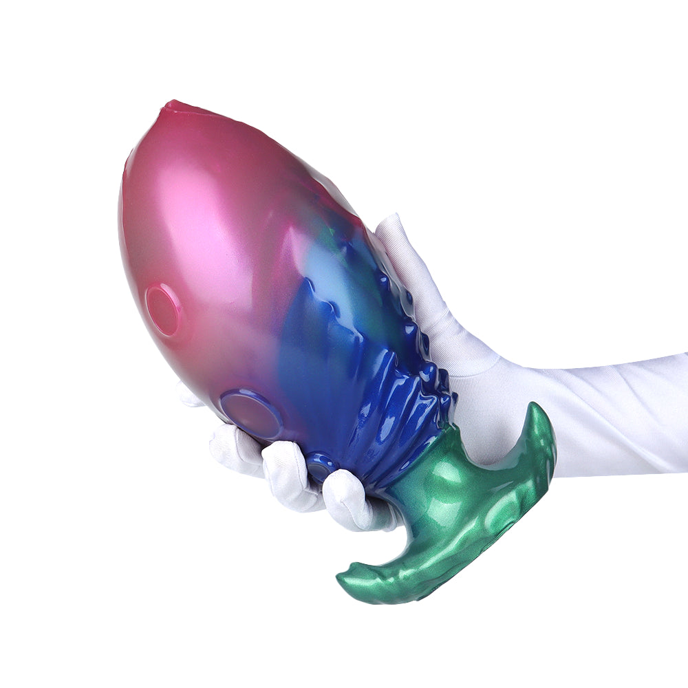 A hand wearing a white glove holding a large gradient-colored fantasy octopus butt plug to show its realistic hand scale.