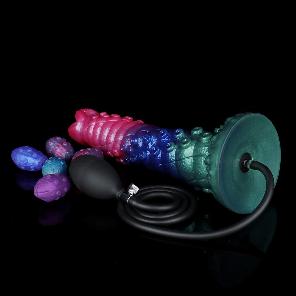 Bottom view of the hollow shaft fantasy dildo showing the green suction cup base connected to a black air pump hose next to multiple colored alien eggs.