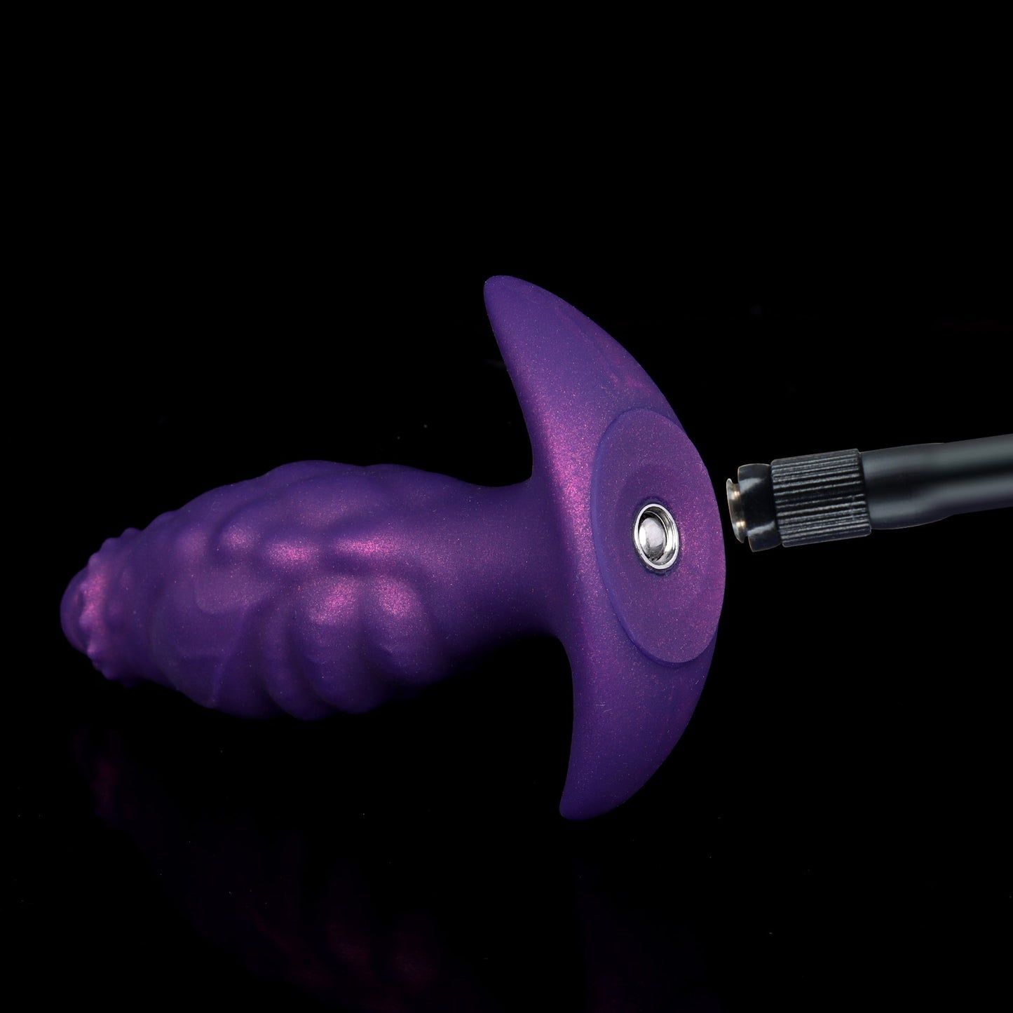 Close-up of the premium metal single-way air valve on the flared base of a purple silicone butt plug with the detachable hose connector.