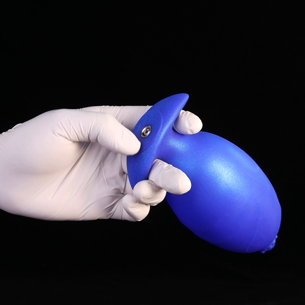 A gloved hand holding an inflated bright blue fantasy tentacle butt plug with a metallic quick-release air valve showing its expanded shape.