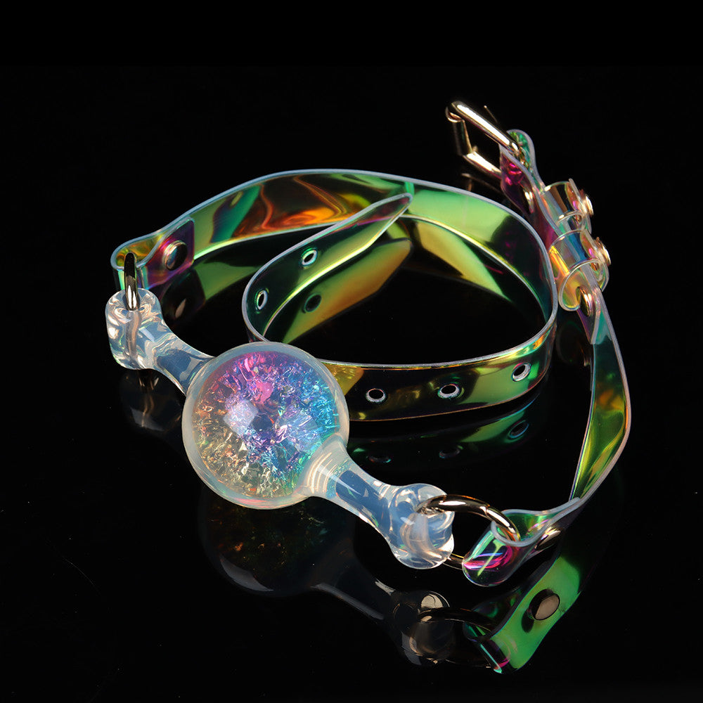 A single light blue crystal ball gag filled with shimmering foil particles and attached to a coiled iridescent laser PVC strap with a gold metal buckle.