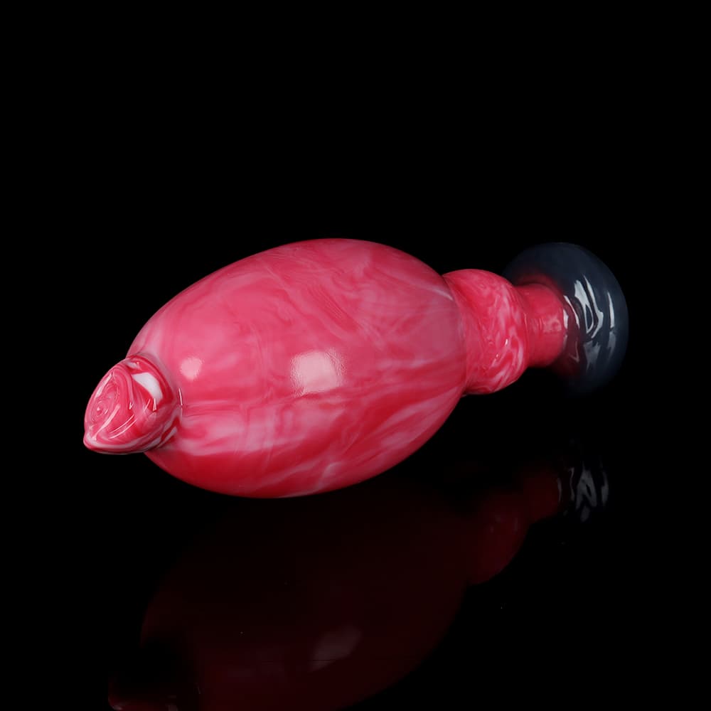 A luxury pink marble expandable anal plug lying horizontally on a reflective black surface, showcasing its sleek bionic rosebud tip.