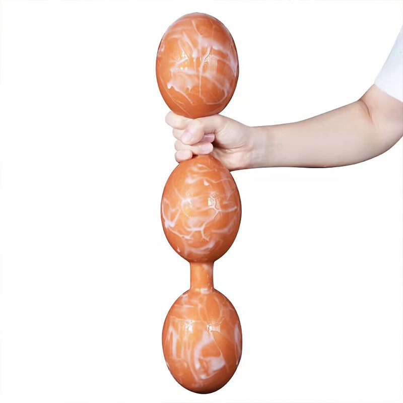 Person holding marble pattern orange three-bead silicone anal plug vertically against white background.