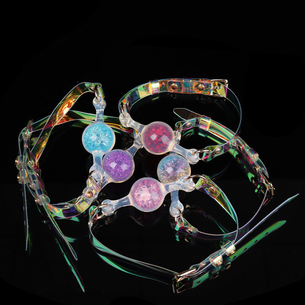 Top view of five different colored cosmic glitter ball gags interwoven together on a black reflective background for alternative roleplay.