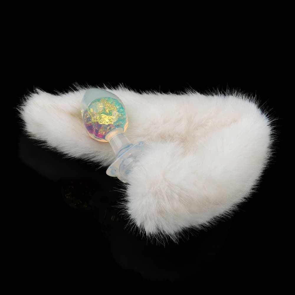 A luxurious glass butt plug with a glowing yellow-blue crystal core attached to a fluffy, soft white faux fur fox tail accessory.