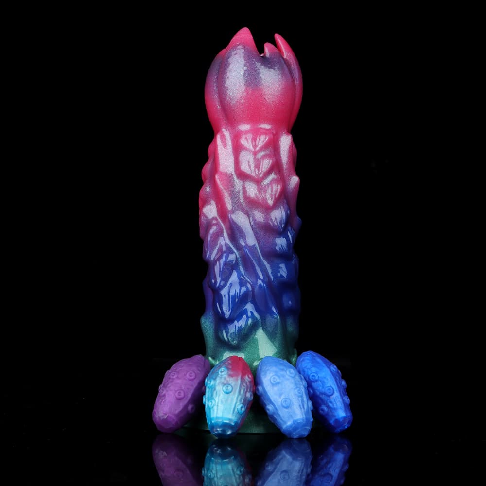 Shimmering green suction cup base of the alien ovipositor dildo with four purple and blue textured egg refills lined up neatly in front on a reflective black surface.