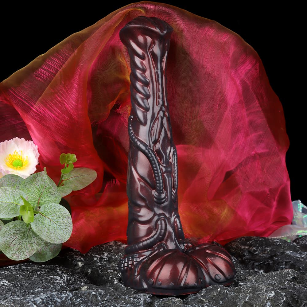 The red and black alien silicone dildo styled with premium red silk fabrics and decorative flowers for a luxury boutique aesthetic.