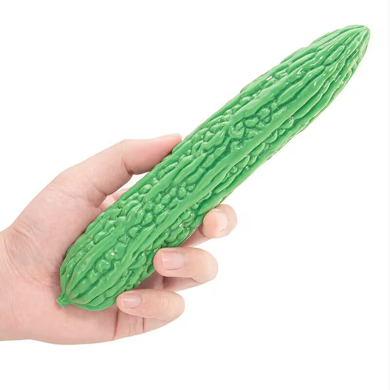 Hand holding a straight green bitter melon silicone dildo highlighting ribbed texture for internal stimulation.