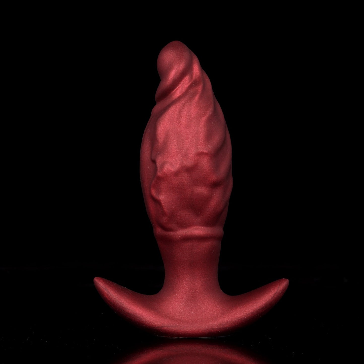 Front view of a crimson red expandable silicone butt plug with organic flame rippled texture and safe flared anchor base for advanced anal training.