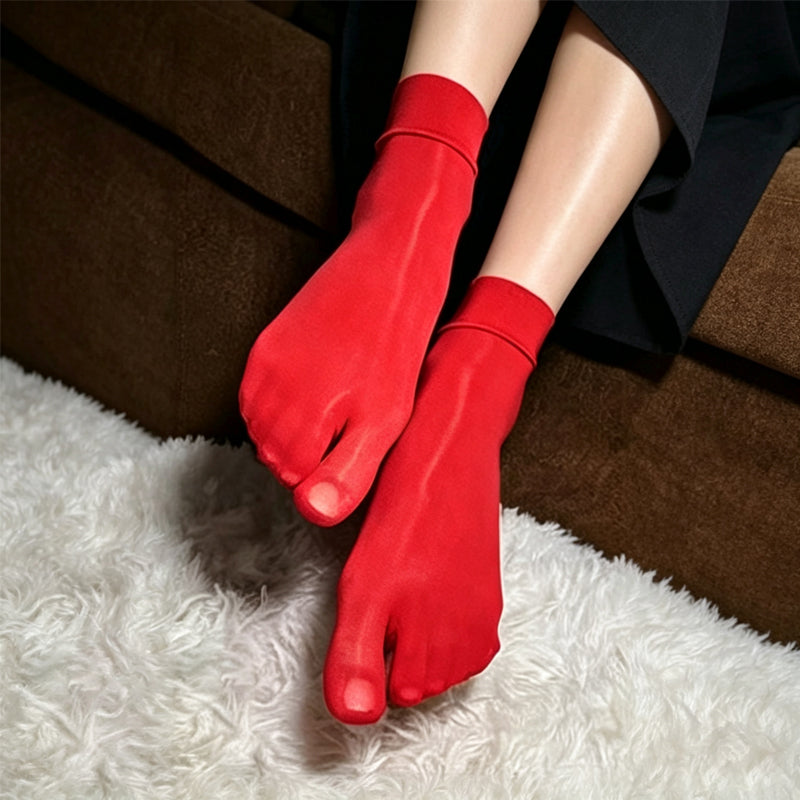 Vibrant red silky sheer five-toe ankle socks displayed on soft rug.